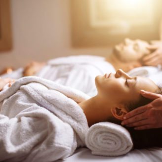 happy young beautiful couple enjoying head massage at the spa