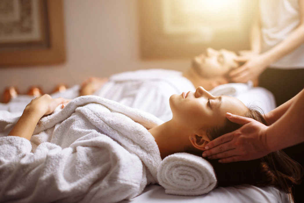 happy young beautiful couple enjoying head massage at the spa