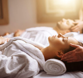 happy young beautiful couple enjoying head massage at the spa